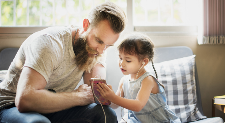 Kleines Mädchen zeigt ihrem Vater was sie gerade auf dem Smartphone sieht.