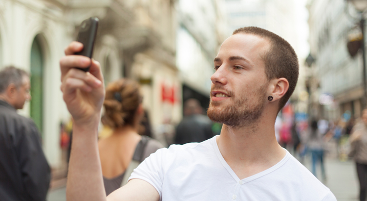 Ein Mann macht ein Bild mit seinem Handy auf der Straße