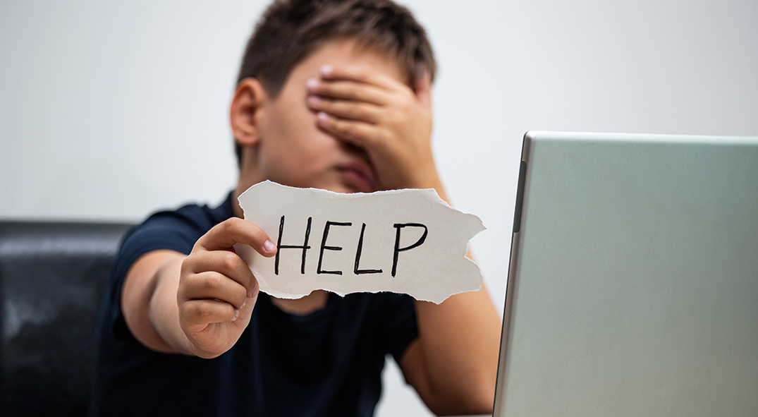 Junge hält sich die Augen zu und hält eine "Help"-Schild in die Kamera