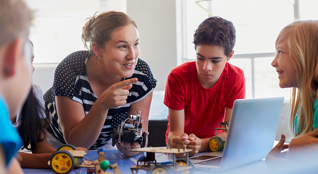 Erzieherin erklärt Kindern wie ein programmierbarer Roboter funktioniert.