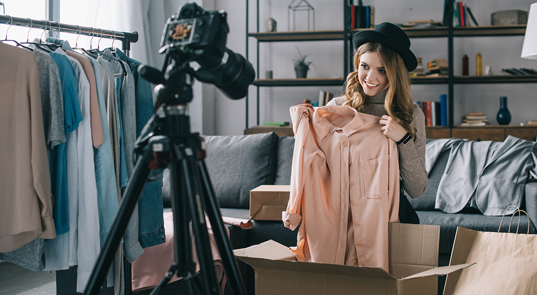 Junge Influencerin vor der Kamera probiert ihr Kleidung an.