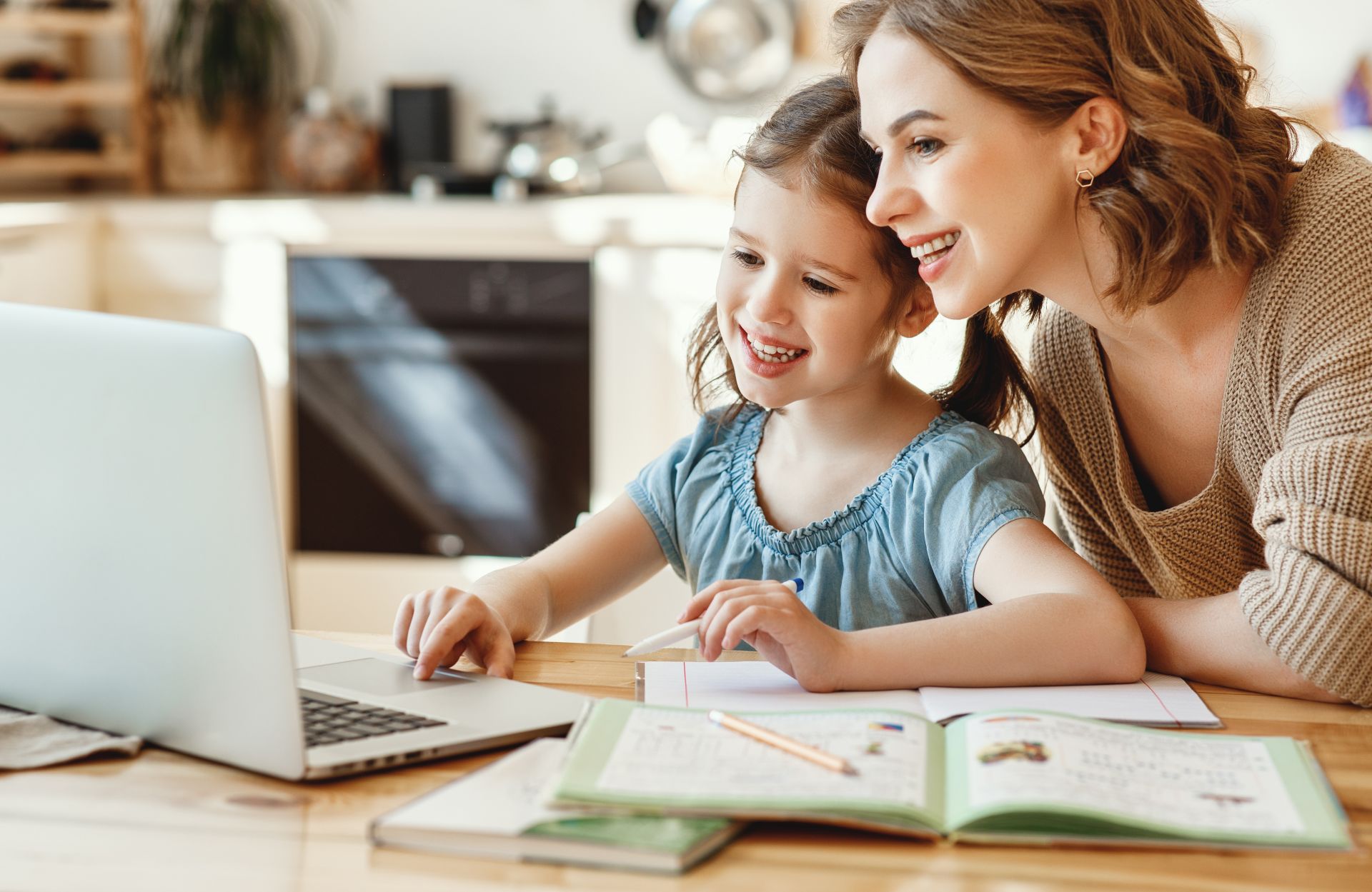 Mutter hilft ihrer Tochter bei den Hausaufgaben am Laptop.